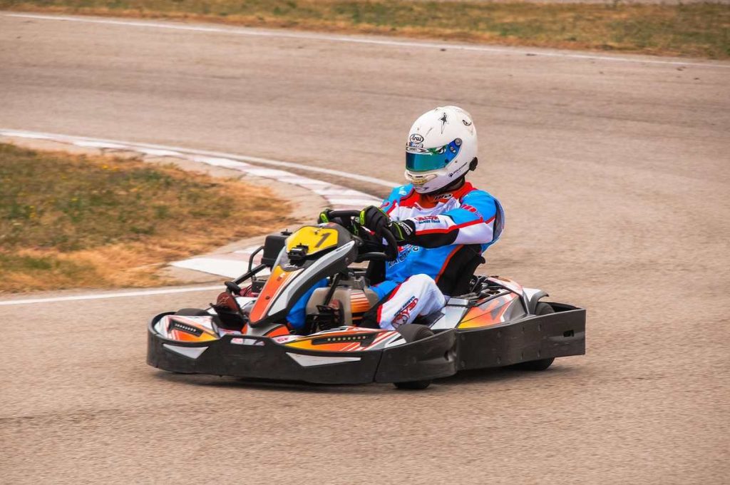 Un pilote en kart coloré tourne sur une piste de ciment