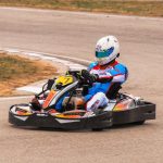 Un pilote en kart coloré tourne sur une piste de ciment