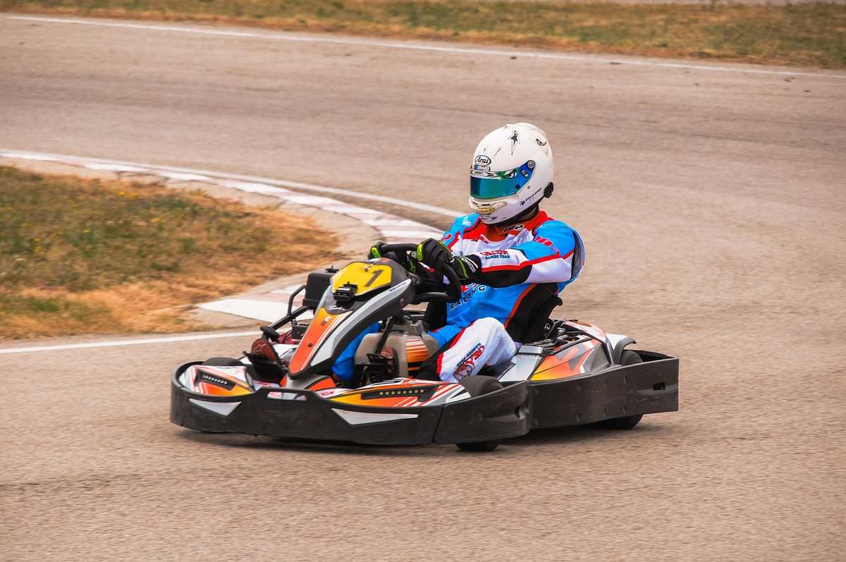 Un pilote en kart coloré tourne sur une piste de ciment